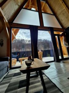 een woonkamer met een tafel en een groot raam bij Amurg in Lupeni