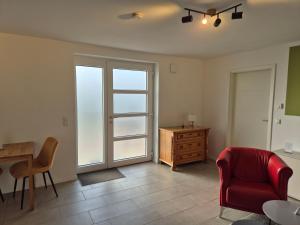 un soggiorno con una sedia rossa e un tavolo di Ferienwohnung - ZeitRaum a Gemünden