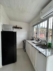 eine Küche mit einem schwarzen Kühlschrank und einer Spüle in der Unterkunft Casa, Punta del Este in Punta del Este