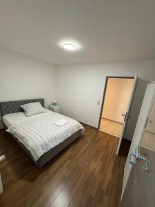 een witte slaapkamer met een bed en een houten vloer bij Elegantes City-Apartment im MG-Zentrum in Mönchengladbach