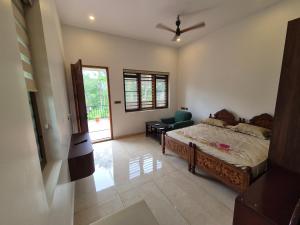 a bedroom with a bed and a chair and a window at Prabhu Villla Upper Deck in Perumpāvūr