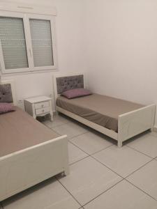 twee bedden in een witte kamer met twee ramen bij Villa guelta 