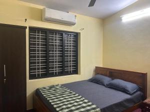 1 Schlafzimmer mit einem Bett und einem Fenster mit Klimaanlage in der Unterkunft Bluebell Homes B- 2bhk in Kozhikode
