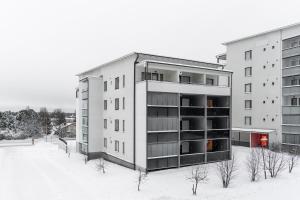 an apartment building with snow in front of it at Scandi Forest Flat Across from the Train Station in Rovaniemi