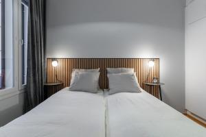 a bedroom with a large white bed with two pillows at Scandi Forest Flat Across from the Train Station in Rovaniemi