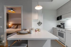 a white kitchen with a table and a living room at Scandi Forest Flat Across from the Train Station in Rovaniemi