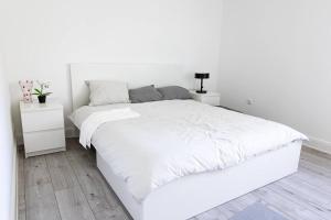 een witte slaapkamer met een groot wit bed en 2 nachtkastjes bij Dailes in Dzelmes