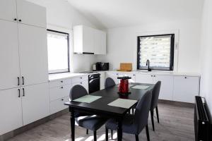 een keuken met witte kasten en een zwarte tafel en stoelen bij Dailes in Dzelmes