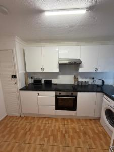 eine Küche mit weißen Schränken und einer schwarzen Arbeitsplatte in der Unterkunft Modern Rooms in North London in Edmonton