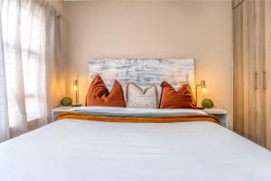 een slaapkamer met een groot bed met oranje kussens bij Retro Pop FREE Parking Fast Wifi Pool Large Workspace in Sandton +23 foto's