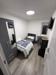 ein Schlafzimmer mit einem Bett, einem Schreibtisch und einem Spiegel in der Unterkunft Modern Rooms in North London in Edmonton