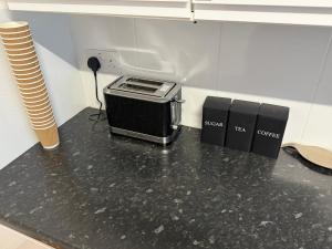 eine schwarze Arbeitsplatte mit einem Toasterofen darauf in der Unterkunft Modern Rooms in North London in Edmonton