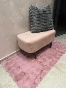 a chair sitting on a pink rug with a pile of blankets at ELLA LUX APARTMAN Čačak in Čačak +8 photos