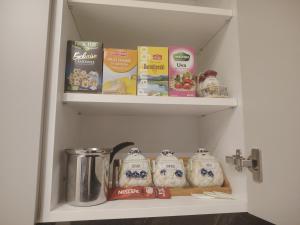 a kitchen shelf with some food and books at ELLA LUX APARTMAN Čačak in Čačak +8 photos