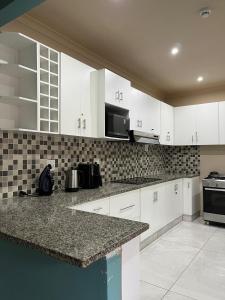 una cucina con mobili bianchi e un piano di lavoro di Crème de la crème a Durban Altre 11 foto