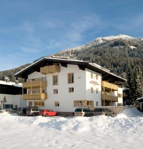 een groot gebouw met auto's geparkeerd in de sneeuw bij Appartements Barbara in Westendorf