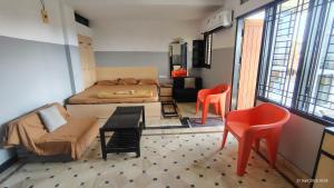 a bedroom with a bed and two orange chairs at NIRMAN beach homestay in Puri