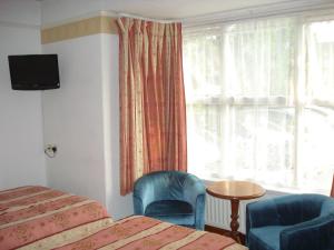 a hotel room with a bed and two chairs and a window at Masslink Guest House in Horley