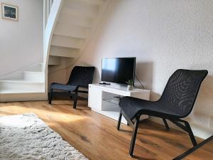 twee zwarte stoelen in een woonkamer met een televisie bij O paradis in Beaune