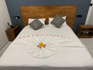 a white bed with a flower on top of it at Havaa Inn Dhangethi in Dhangethi +25 photos