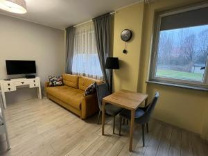 een woonkamer met een bank, een tafel en een raam bij Apartament COMFORT Centrum in Krotoszyn