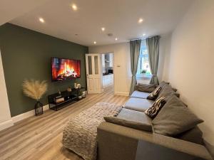 a living room with a couch and a tv on the wall at Adrian Cottage in Abbots Langley