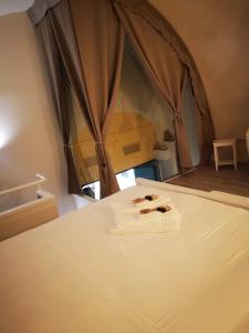 een slaapkamer met een bed met witte lakens en een raam bij Dimora Daliah&Oana in Matera