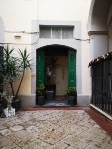 een groene deur in een wit gebouw met potplanten bij Dimora Daliah&Oana in Matera