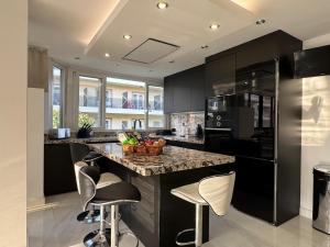 a kitchen with black cabinets and a counter with stools at Apartamento IMPERIO 2 - Marbella centro in Marbella