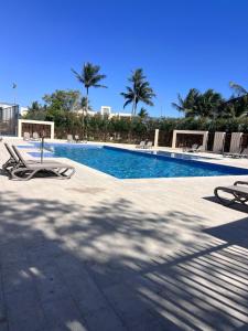 a swimming pool with two lounge chairs and palm trees at Hawana Apartment in Salalah