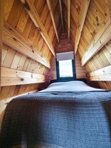 Bett in einer Holzhütte mit Fenster in der Unterkunft Chalé da Cumieira Nova in Seia
