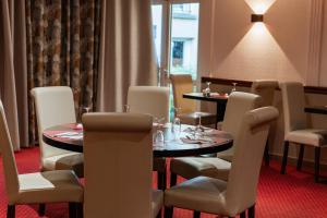 a dining room with two tables and chairs and a table and chairsktop at BRIT HOTEL Le Lion d'Or CHINON in Chinon