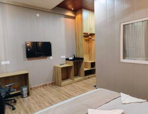a hotel room with a bed and a tv at Sunrise Vista Resort & Hotel in Bāgeshwar