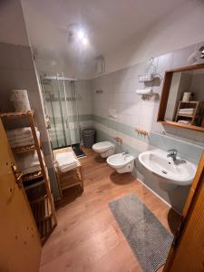 een badkamer met een wastafel, een toilet en een spiegel bij Tesino Appartamenti in Castello Tesino +21 foto's