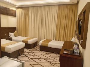 a hotel room with two beds and a flat screen tv at فندق الكشاف المتقدم توصيل للحرم مجاني in Mecca