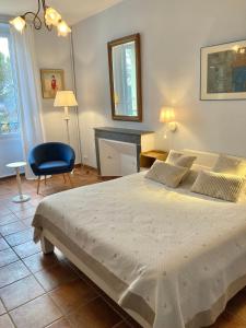 een slaapkamer met een groot bed en een blauwe stoel bij La Bastide de Villecroze in Villecroze