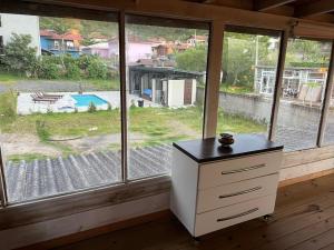 a dresser in a room with a large window at Chalé da Joaquina in Florianópolis