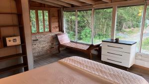 a bedroom with a bed and a chair in a cabin at Chalé da Joaquina in Florianópolis