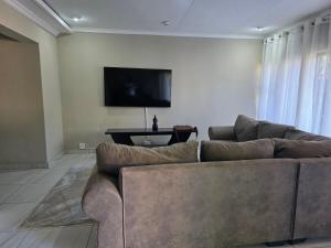 un soggiorno con divano e TV a schermo piatto di 55 on 5th a Lichtenburg