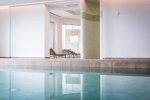 una piscina con 2 sillas en un edificio en Kronplatz-Resort Hotel Kristall en Valdaora