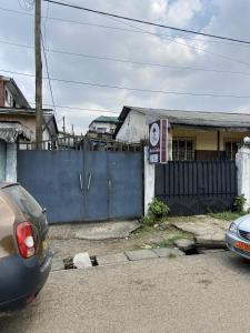 due auto parcheggiate davanti a una recinzione blu di 1 Bedroom Apartment a Douala