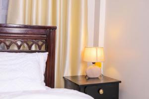 a bedroom with a bed and a lamp on a night stand at Kj suites in Meru