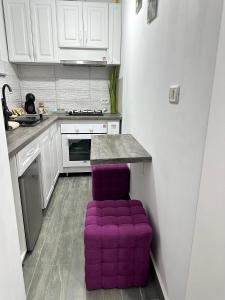 a kitchen with a purple padded stool in a kitchen at White Studio in Câmpulung Moldovenesc +3 photos