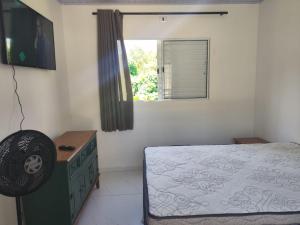 a bedroom with a bed and a dresser and a window at Casa Aconchegante in Bertioga