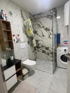 a bathroom with a toilet and a washing machine at Apartament in Ferizaj