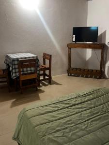 een slaapkamer met een bed, een tafel en een tv bij Habitaciones Monarcas in Villa Carlos Paz