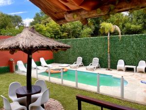 een zwembad met stoelen en een parasol bij Verano Paz in Villa Carlos Paz