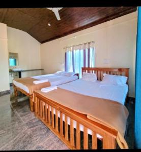 a bedroom with two beds and a desk in it at Stone Guest House Gokarna in Gokarn