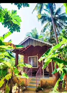 a house with a porch and some palm trees at Stone Guest House Gokarna in Gokarn
