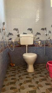 a bathroom with a toilet and a wall with birds on it at Stone Guest House Gokarna in Gokarn